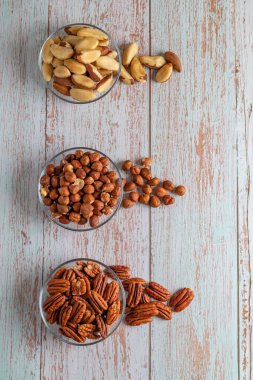 Tahta bir masada üç çeşit fındık, sağlıklı yağ ve protein yiyeceği, vegan, ketojenik diyet, bitki temelli diyet, iyi bir uyku ve rahatlama için doğal triptofan kaynakları, kopyalama alanı, kapanış.