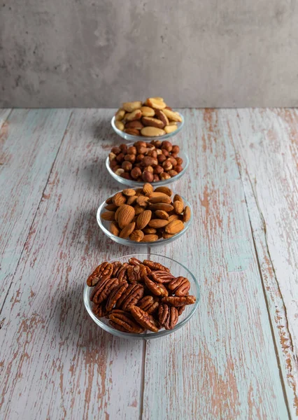 Tahta bir masada dört çeşit fındık, sağlıklı yağ ve protein yiyeceği, vegan, ketojenik diyet, bitki temelli diyet, iyi bir uyku ve rahatlama için doğal triptofan kaynakları.