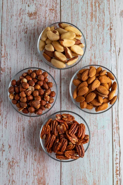 Tahta bir masada dört çeşit fındık, sağlıklı yağ ve protein yiyeceği, vegan, ketojenik diyet, bitki temelli diyet, iyi bir uyku ve rahatlama için doğal triptofan kaynakları, kopyalama alanı, kapanış.