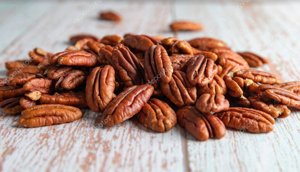 A pile of natural pecan kernels on a wooden table, healthy fat and protein food, vegan, ketogenic nutrition concept, plant-based diet, close up, copy space