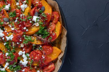 Lezzetli Hokkaido balkabağı körili, mini domatesli, fındıklı, kabak tohumlu, hurma ve koyun peynirli, koyu kırsal bir zeminde pişirilmiş..