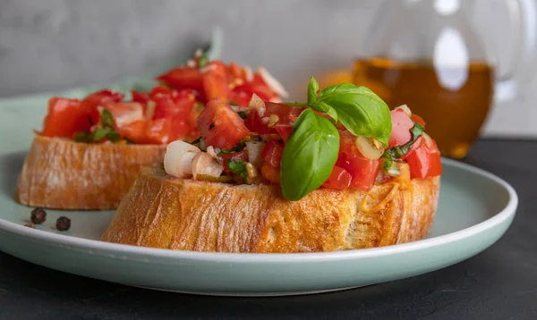 Dua potong tomat bruschetta yang terbuat dari roti ciabatta dengan tomat dadu, rempah-rempah, kemangi dan bawang putih cincang di atas piring, masakan Italia, fokus selektif — Stok Foto
