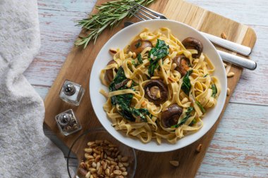 Kremalı mantarlı ıspanaklı makarna. Mantarlı Rustik makarna, kremalı ıspanak sosu ve ahşap arka planda maydanoz..