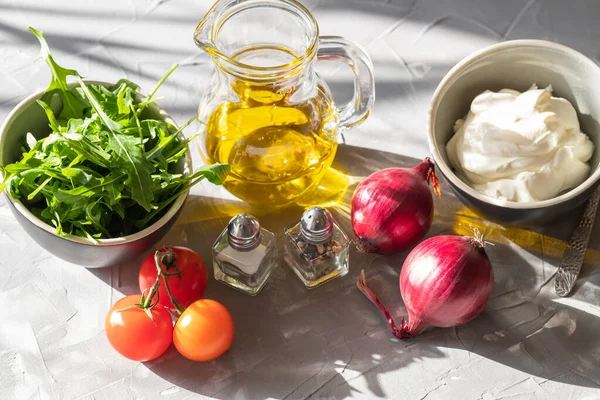 Gri bir arka planda tarte roka, domates, soğan, mantar, biber, mozarella ve baharat kavanozlarının karışımı..