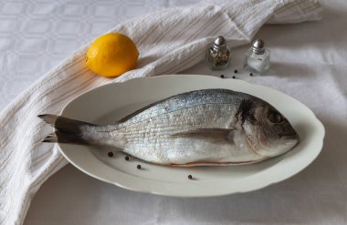 Izgara için beyaz bir tabakta çipura hazırla.