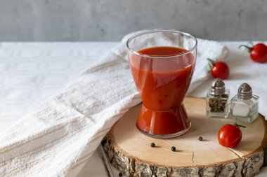 Gri arkaplanda domates suyu, biber, tuz ve domatesli bardak..