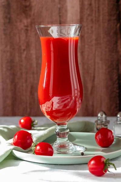 Glas mit Tomatensaft, Pfeffer, Salz und Tomaten auf einem hölzernen Hintergrund — Stockfoto