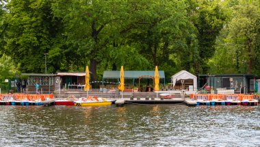 Berlin-Treptow, Almanya - 21 Mayıs 2022, Kulturinsel, Insel der Jugend karşısındaki Treptower Park 'ta restoranları ve birkaç tekne kiralama ile Spree manzarası. Gezi tekneleri nehirde yüzüyor..