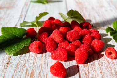 Eski ahşap masada bir avuç kırmızı olgun ahududu, yakın.