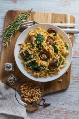 Kremalı mantarlı ıspanaklı makarna. Mantarlı Rustik makarna, kremalı ıspanak sosu ve tahta arka planda maydanoz, dikey