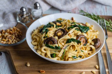 Kremalı mantarlı ıspanaklı makarna. Mantarlı Rustik makarna, kremalı ıspanak sosu ve ahşap arka planda maydanoz.