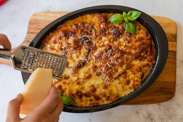 Moussaka- shot from above. Traditional Greek dish made with baked layers, eggplant, meat, bechamel sauce and topped with basil leaves and grated Parmesan cheese.