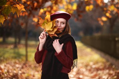 Beautiful brunette turned around and looks enthusiastically into the distance. Holing maple leaves