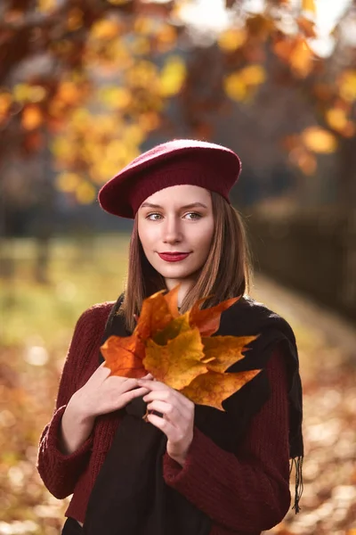 Stylish happy smiling woman posing in the park. Wearing a french beret.