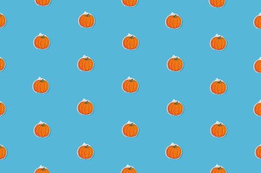 Autumn pattern with small pumpkins on a blue background. Abstract concept idea.