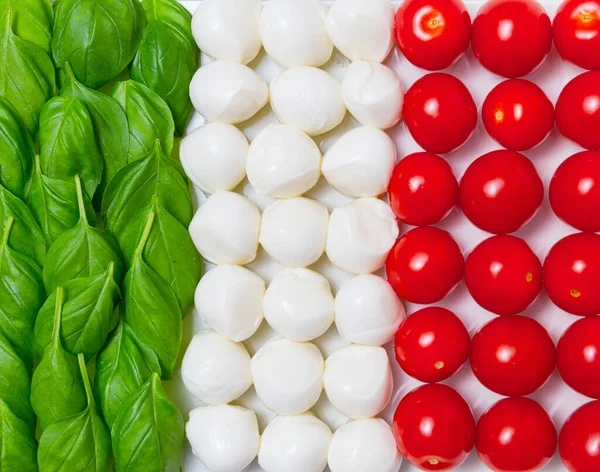 Italian flag made of organic basil, mozzarella cheese and cherry tomatoes on a white background. Advertisement for traditional Italian and Mediterranean cuisine. Concept idea.