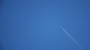 Yazın mavi gökyüzünde hareket eden uçaklar, güneşli bir yaz gününde iki beyaz duman şeridi bırakarak mavi gökyüzünde hızla uçan çağdaş bir uçağın iki beyaz çizgisi çiziyor. İyimser görünüyor..
