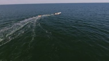 Turistik halkanın Karadeniz 'deki bir sürat teknesinin çektiği turistik bir görüntüsü. Gülünç beyaz motorlu tekne, turistlerle birlikte Karadeniz' de şişme halkayı çekiyor. Yazın güneşli bir günde köpüklü dalgaların izlerini bırakıyor..
