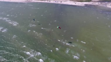 Karadeniz kıyılarının dalgalı suları ve rüzgar sörfçüleri ile hava görüntüsü Karadeniz kıyılarının rüzgar sörfçüleri, paraşütler, güneşli bir günün ışınları altında dalgalanan dalgalar ve yazın kumlu sahillerde parlayan kuş bakışı görüntüsü heyecan verici.. 