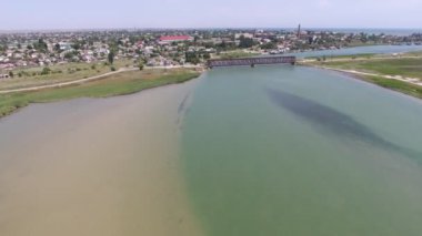 Arabat okunun kısa bir köprüsü, kıvrımlı bir yolu ve güneşli bir yaz gününde çağdaş ve kısa bir köprüsü ve yılanlı bir yolu olan Arap okuna ait heyecanlı kuş bakışı küçük bir köy görüntüsü. Altında Karadeniz suları.