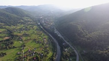 Yaz aylarında Karpat Vadisi 'nden geçen bir otoban ve nehir yatağının havadan çekilmiş görüntüsü. Yazın kurumuş nehir yatağı ve otomobille kaplı yeşil vadi boyunca uzanan modern otoban manzaralı etkileyici bir kuş bakışı.