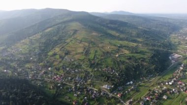 Yazın en alt kısımlarında yollar ve evler bulunan Karpatlar 'a ait yollar, evler, tarlalar ve çayırların olduğu uzun bir Karpatlar sırtı manzaralı sersemletici kuş bakışı bir yaz günü.