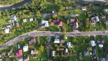 Güneşli bir günde Karpatya bölgesinde giden arabalarla bir otoyolun görüntüsü Karpat Dağları 'ndaki küçük binalar, yeşil parklar, sokaklar, güneşli bir sonbaharda hareket eden otomobillerle çağdaş bir otoyolun görüntüsünü hayrete düşürüyor.