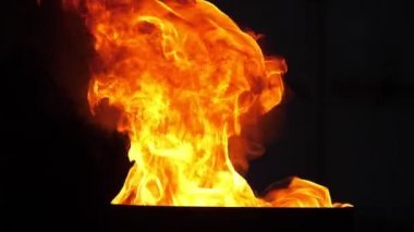 Kırmızı ve turuncu ateş alevleri, siyah arka planda ağır çekimde fırında dans ediyor. Kırmızı, sarı ve turuncu renkli dumanlı çatallar ağır çekimde fırında yanıyor. Sihirli, güzel ve büyüleyici görünüyor..