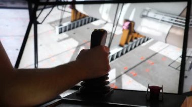 İşçi eli, vinç kokpitinde bir tutacağa ve atölyede dönen boruya basıyor. Çalışan birinin elinin, geniş ve şeffaf pencereleri olan çağdaş bir yengeç kokpitini çekerek metal yapılara sabitlenmiş bir boruyu çevirmesi etkileyici.