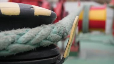 Büyük bir naylon ip yuvarlanıyor ve geniş bir kordondan açık havaya doğru hareket ediyor. Metalik bir kazıktan, sonbaharda bir atölyenin bahçesindeki geniş metalik bir vince dönen ve hareket eden büyük bir naylon çekicinin etkileyici görüntüsü..