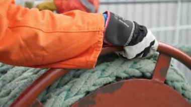 Üniformalı bir işçi, beyaz naylon kablo yerleştiriyor ve güneşli bir sonbaharda büyük bir vinç sallıyor. Turuncu üniformalı, naylon bir kablo örten ve sonbaharda bir atölyede açık havada dolaştıran profesyonel bir işçinin neşeli yakın çekimi..