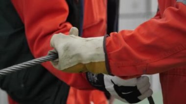 Profesyonel işçiler, sonbaharda turuncu üniformalı iki profesyonel adam ve sonbaharda beyaz eldivenli iki profesyonel adamın yardımıyla naylon kablo döşeyerek yuvarlanan bir Jenny 'yi örterek dönen asansöre bağlıyorlar..