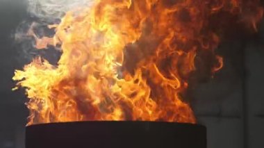 Çok renkli alevlerin alevleri yavaş çekimde siyah arkaplanda bir kazanda yanıyor.