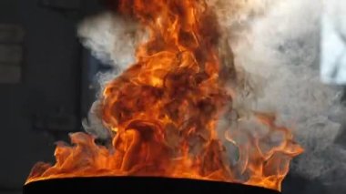 Endüstriyel konteynırların arka planına karşı metal bir varilde yanan bir kutu petrol.