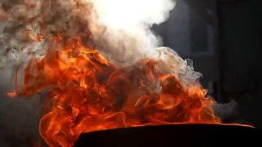 Endüstriyel konteynırların arka planına karşı metal bir varilde yanan bir kutu petrol.