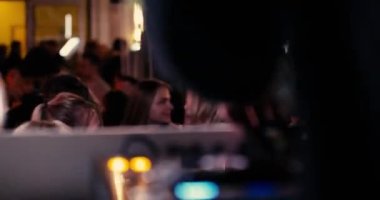 Cheerful people at a night party dancing to music next to a dj. High quality 4k footage