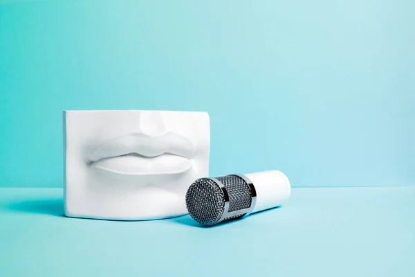 Weißes metallisches Mikrofon mit Steinlippenpodium auf hellblauem Hintergrund. Interview und Podcast-Konzept. — Stockfoto