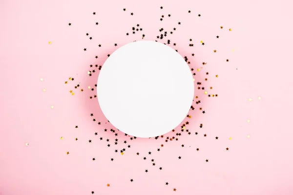 Altın yıldızlar beyaz podyum altında pembe pastel arka planda kozmetik sergisi için konfeti parlıyor.