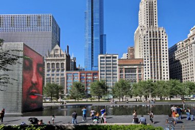  Millennium Park 'taki yansıtıcı havuza değişen yüzleriyle Crown Fountain sıcak bir yaz gününde Chicago' da görüldüğü gibi aileler için popüler bir cazibedir. 