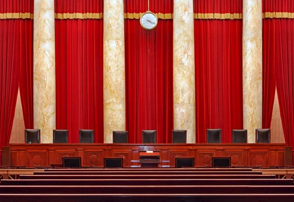 The United States Supreme Court - the seats for the nine powerful judges of the Supreme Court face the courtroom against a red backdrop.