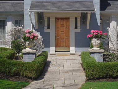 Zarif ahşap kapısı ve kaldırım taşı yolu olan manzaralı bir ev.