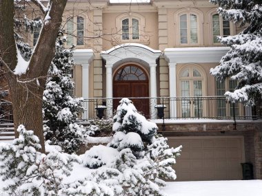 Karla kaplı çam ağaçları olan banliyö evi