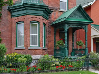 Körfez pencereli eski tuğla ev ve kapısı açık.