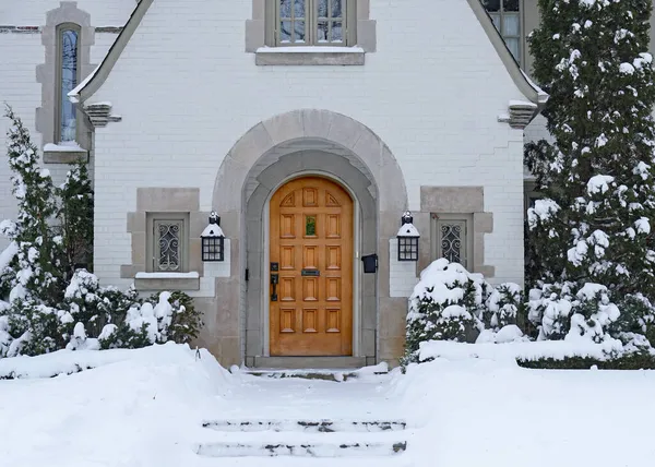 Front door of house with snow covered pine tree