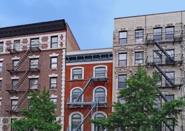 Eski New York apartmanı harici yangın merdivenleri, pencere klimaları ve pencereleri süslemeli.