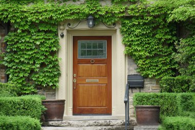 Zarif ahşap kapılı ev sarmaşıklarla çevrili.