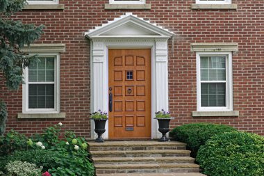 Evin ahşap ön kapısı zarif kaldırım taşı merdivenleri ve çiçekleri var.