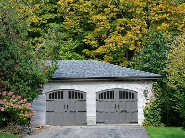 Evin iki araba garajı ağaçlarla çevrili.