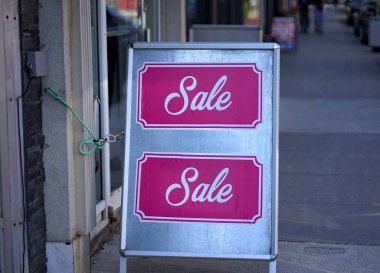 Bir mağazanın önündeki kaldırımda bir sandviç tahtası tabelasına reklam vermek. 