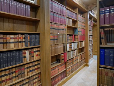 Ahşap kitap rafları ve mühürlü eski yasal metinleri olan bir kütüphane.